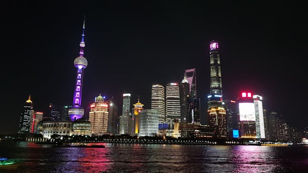 Vibrant night view of Shanghai's illuminated skyline and reflective river.