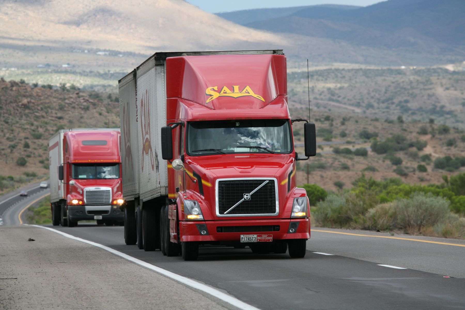 Modern semi trucks traveling through a U.S. highway landscape