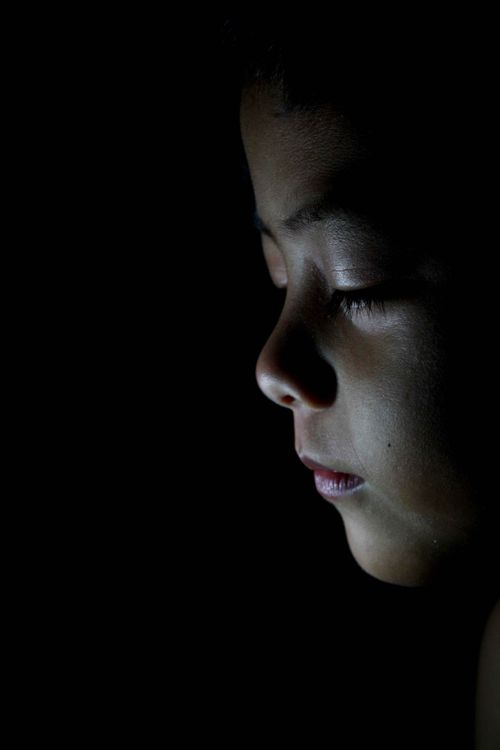 Free Artistic side profile of a child with dramatic lighting in low light setting. Stock Photo