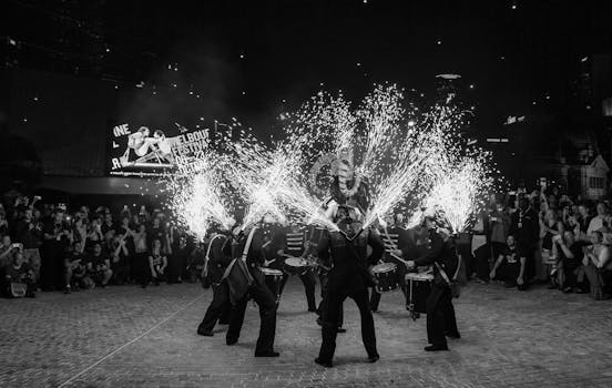 Black and white photo of a lively drum performance with fireworks at a festival.