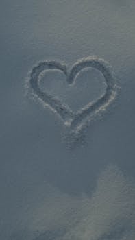 A heart shape gently drawn in the snow, evoking winter romance and seasonal love.