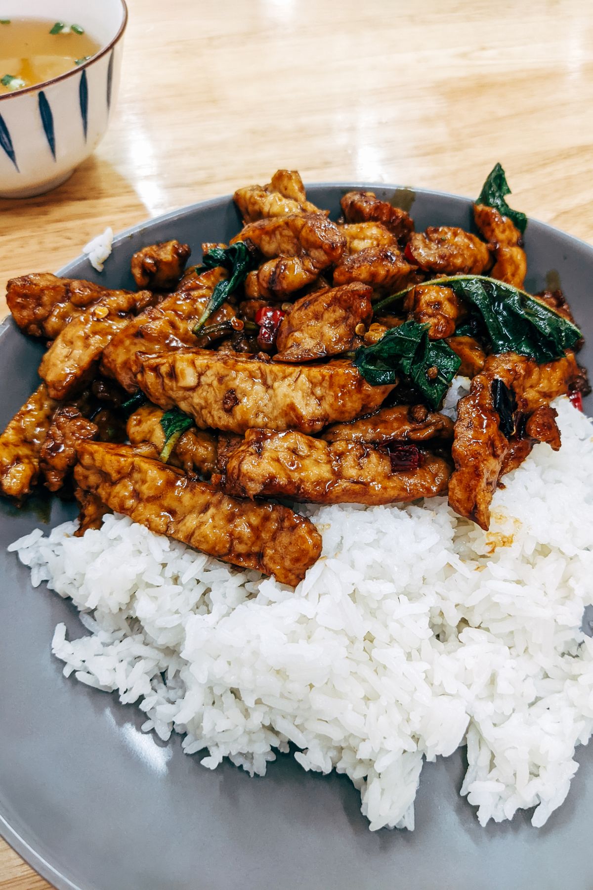 A grey bowl of white rice with roasted tofu and a simple stir-fry, an easy-to-digest pre-race dinner