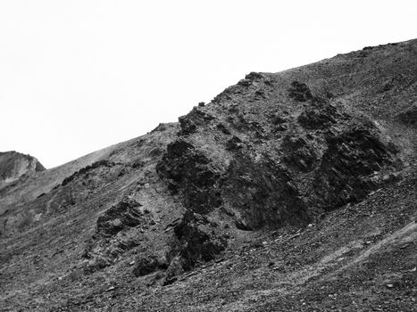 Monochrome image of a rugged rock formation on a mountain slope.
