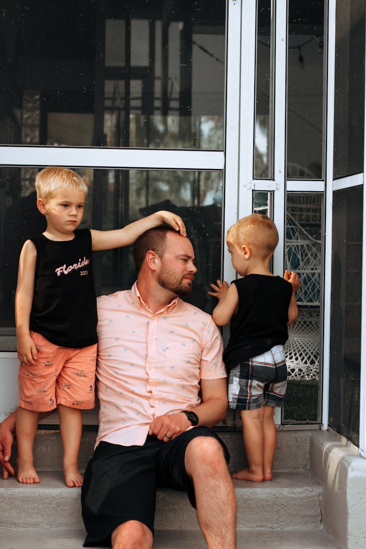 Father Sitting On Steps With His Two Little Sons 