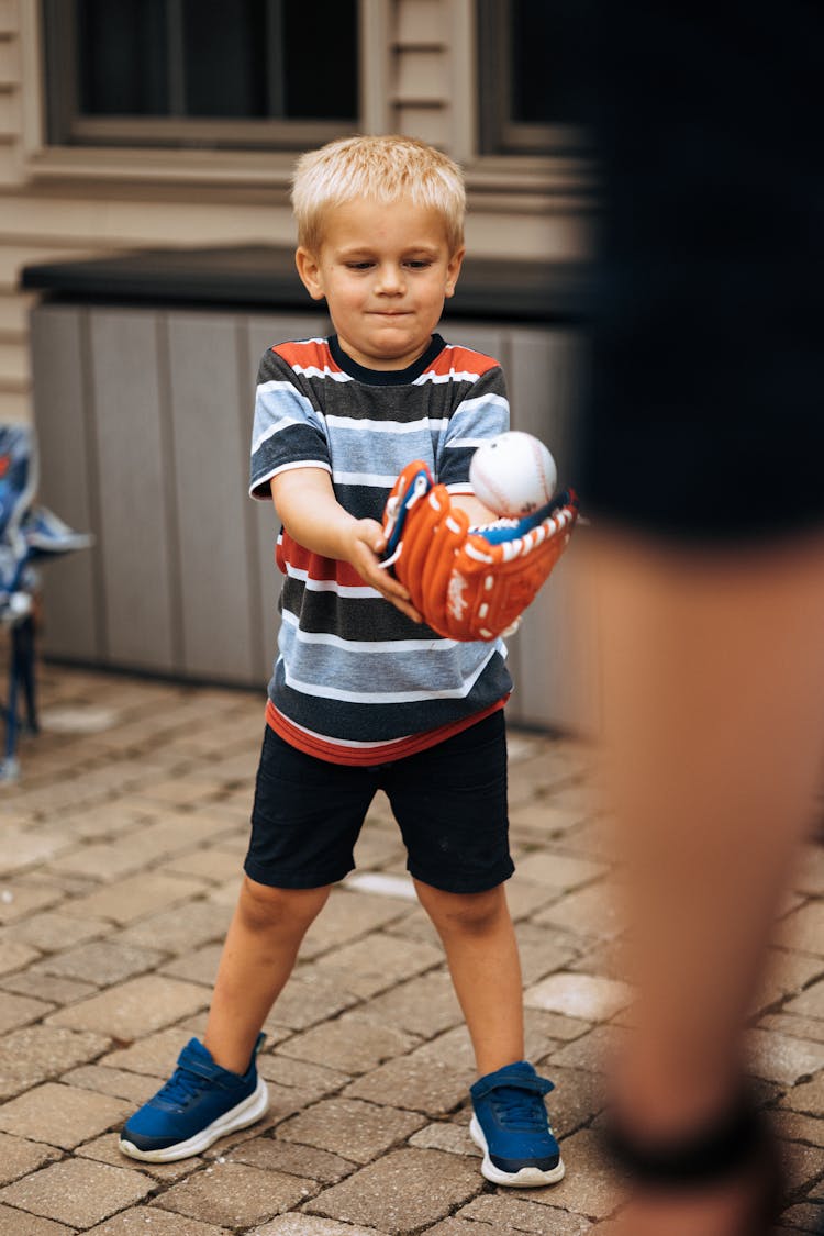 A Boy Catching A Ball While Wearing A Baseball Glove