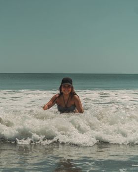 Smiling woman in swimsuit wading in waves at Panama beach, enjoying a sunny day.