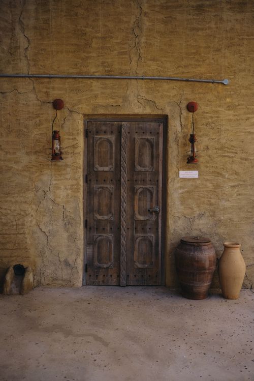 Free Wooden door with vintage charm, surrounded by pottery and rustic lanterns in Dubai. Stock Photo