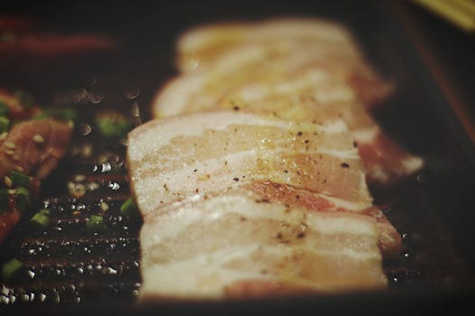 Delicious grilled meat slices seasoned with pepper on a hot sizzling grill, perfect for dinner.