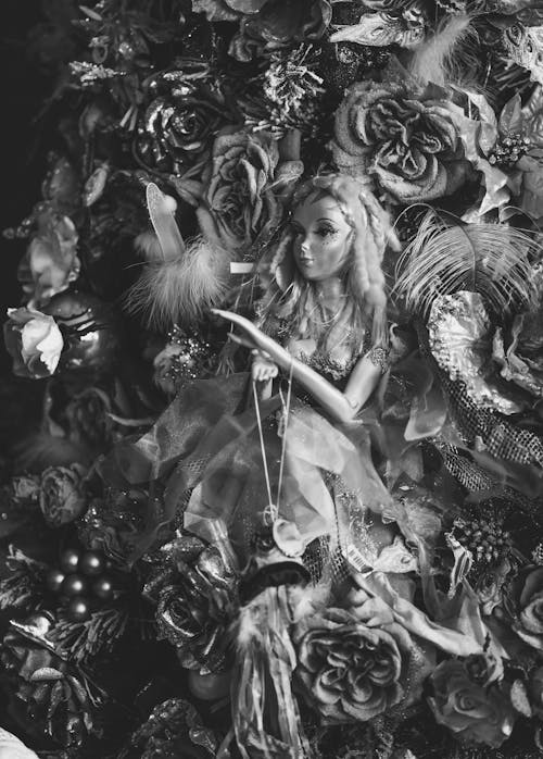 Grayscale Photography of a Doll Surrounded with Flowers