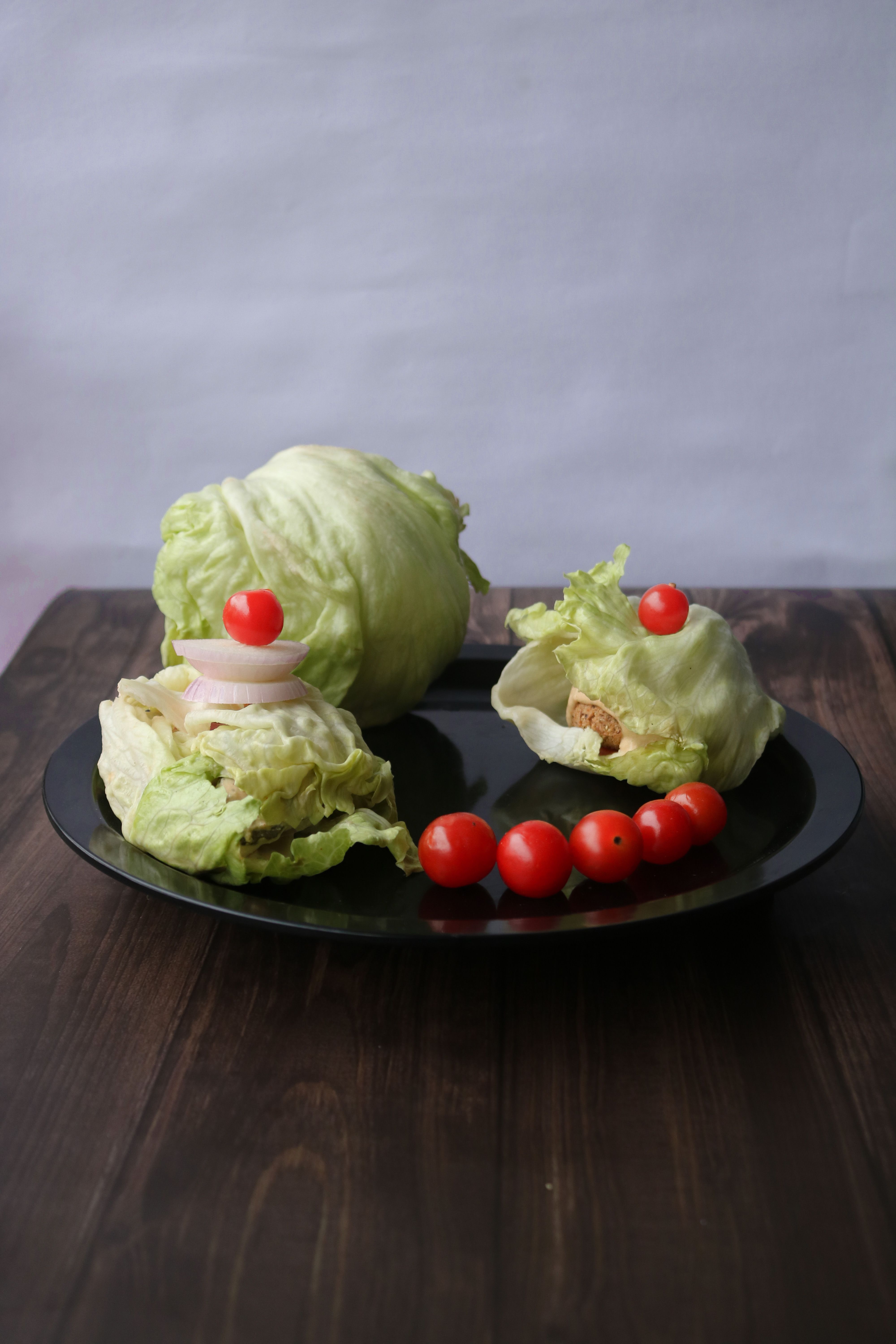 A healthy arrangement of fresh lettuce and cherry tomatoes on a dark plate, perfect for a balanced diet.