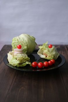 A healthy arrangement of fresh lettuce and cherry tomatoes on a dark plate, perfect for a balanced diet.