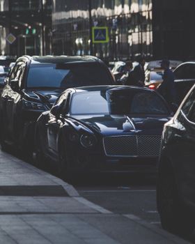 A sleek Bentley car parked on a bustling street in Moscow, Russia at dusk.