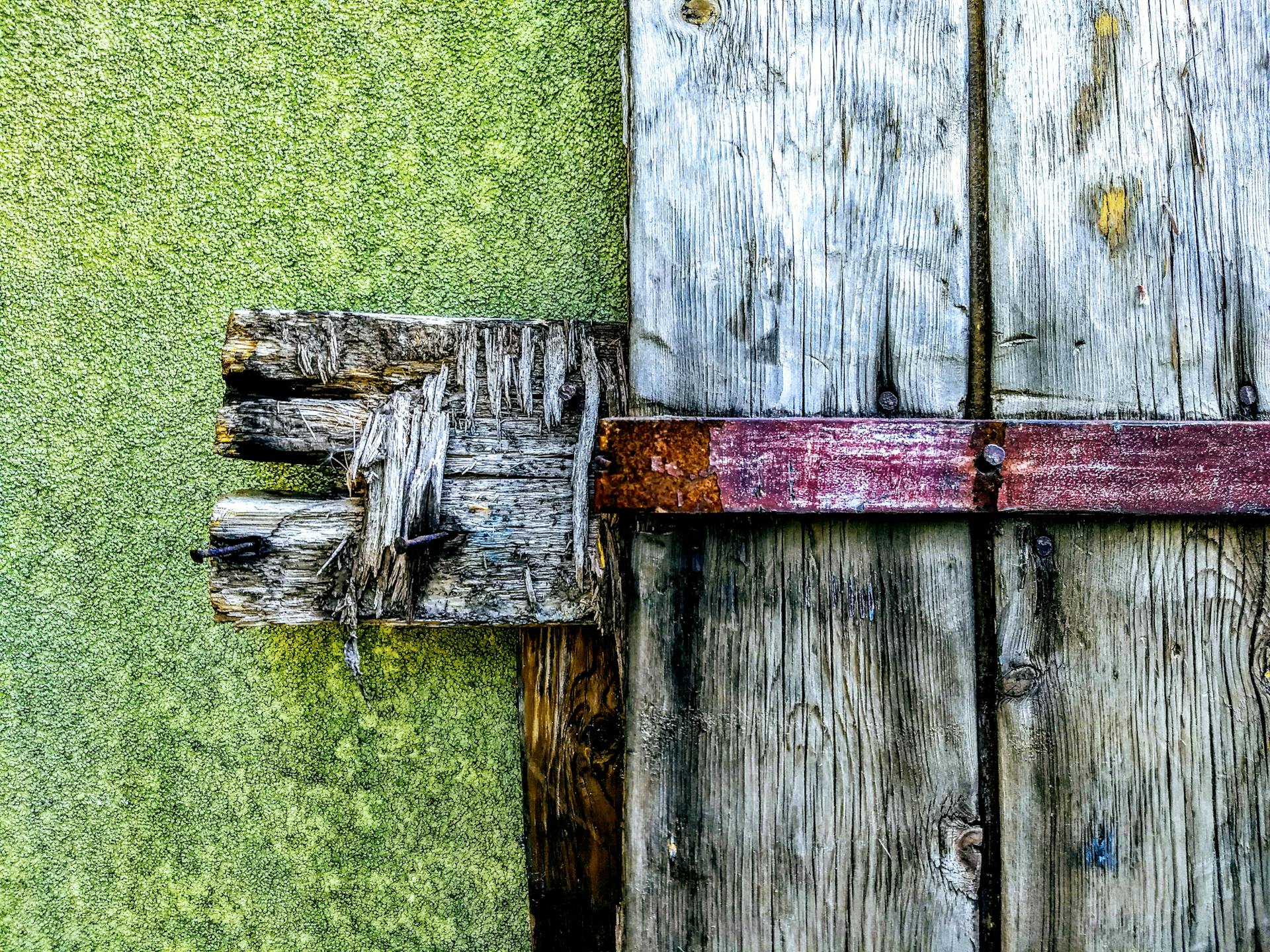 Close-up of a rustic wooden door with a rusty latch and weathered wood texture.