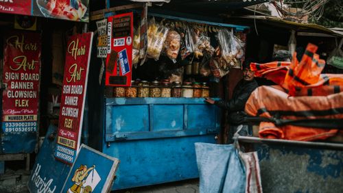 Free A vibrant scene of an Indian street market with a vendor and colorful signage. Stock Photo