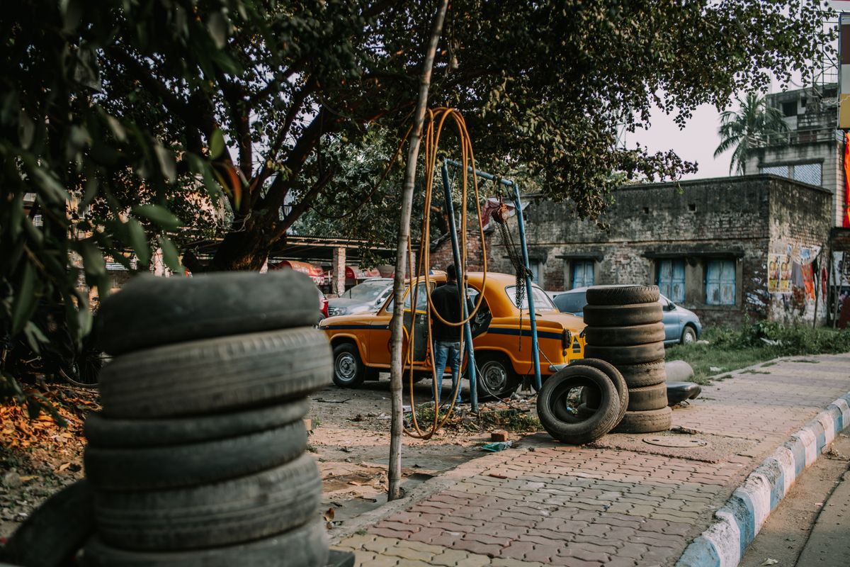 Mechanic at a roadside garage with a car and stacked tyres