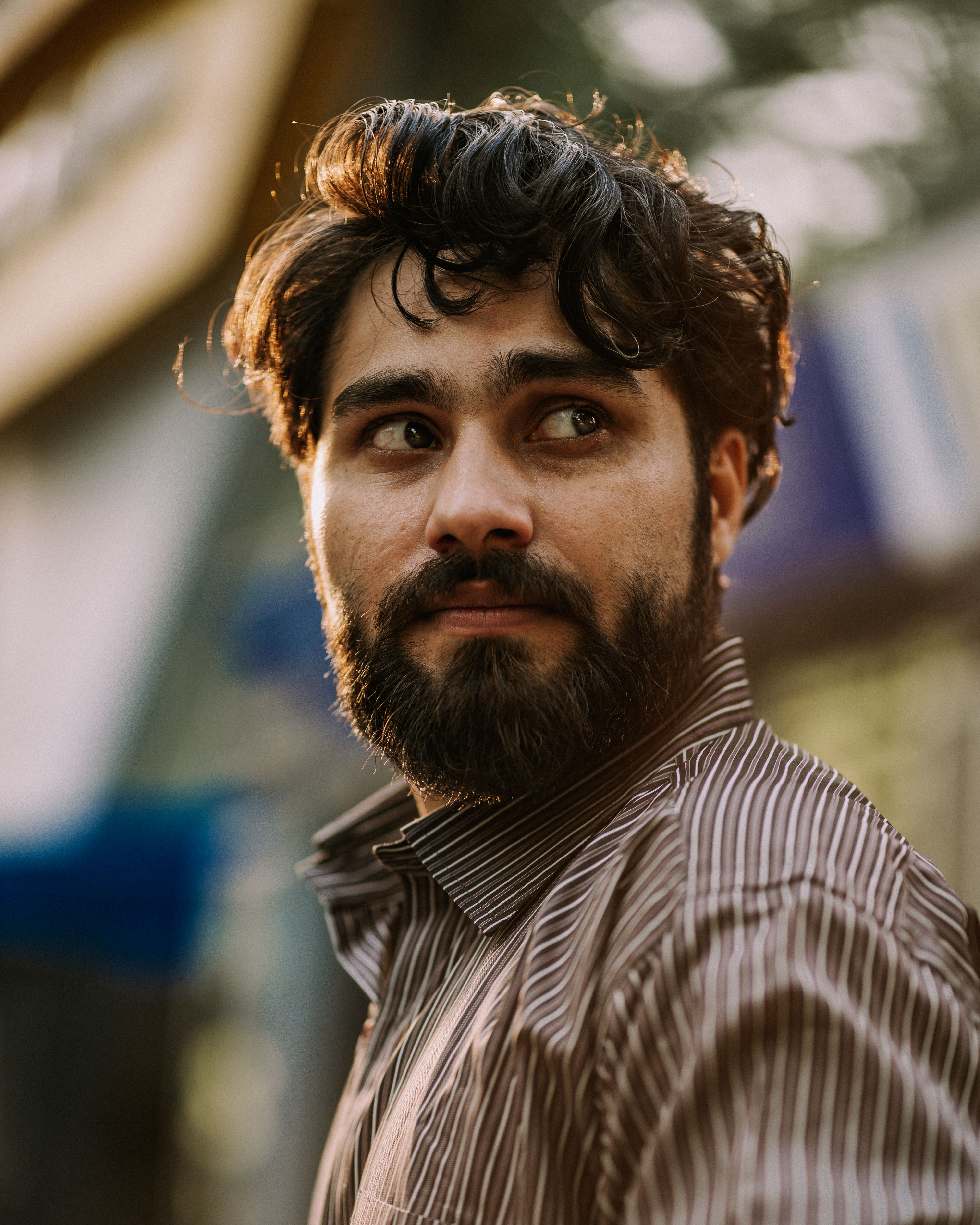 Close-up portrait of a bearded man outdoors with a contemplative expression.