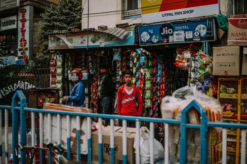 Free Street view of a small Indian shop bustling with vibrant colors and daily activities. Stock Photo