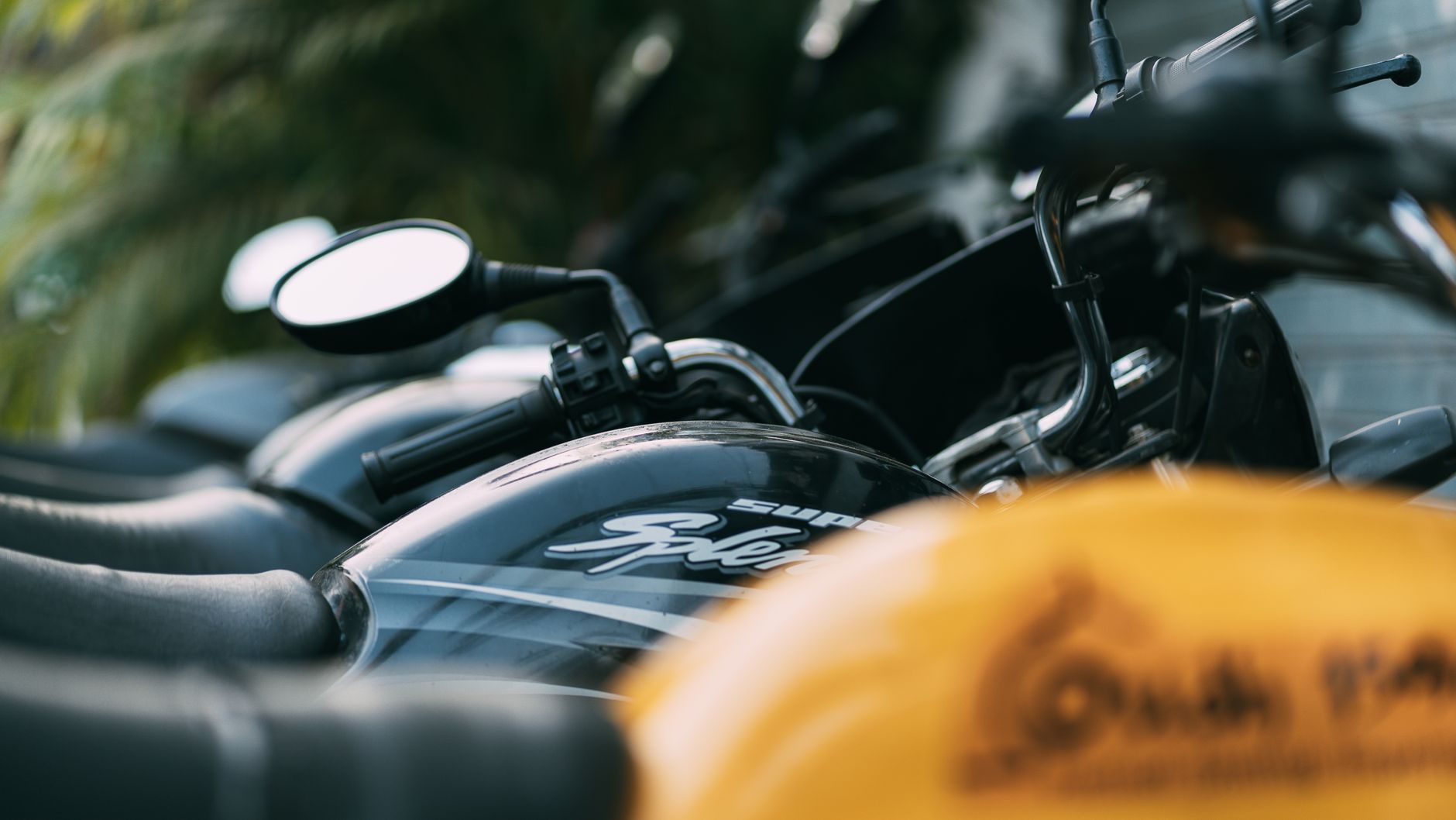 A close-up of parked motorcycles lined up with a focus on the handlebars.