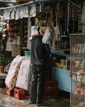 A person shops at a colorful outdoor market stall filled with various products hanging and displayed prominently.