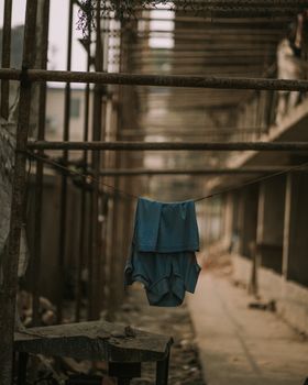 A blue t-shirt hangs on a line in an urban construction site, showcasing daily life contrasts.