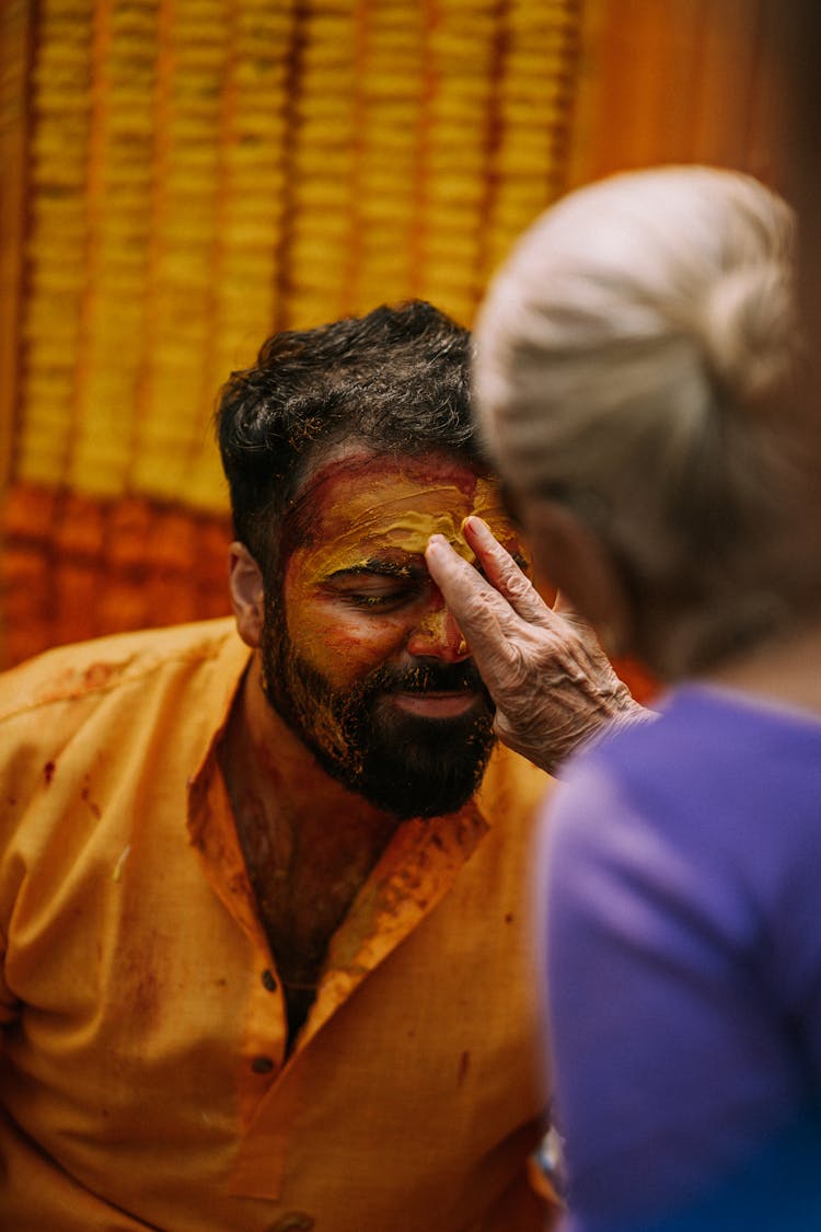 Elderly Woman Painting Man Face