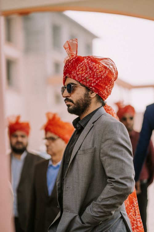 Free Adult man wearing a vibrant red turban and sunglasses, captured during an outdoor event. Stock Photo