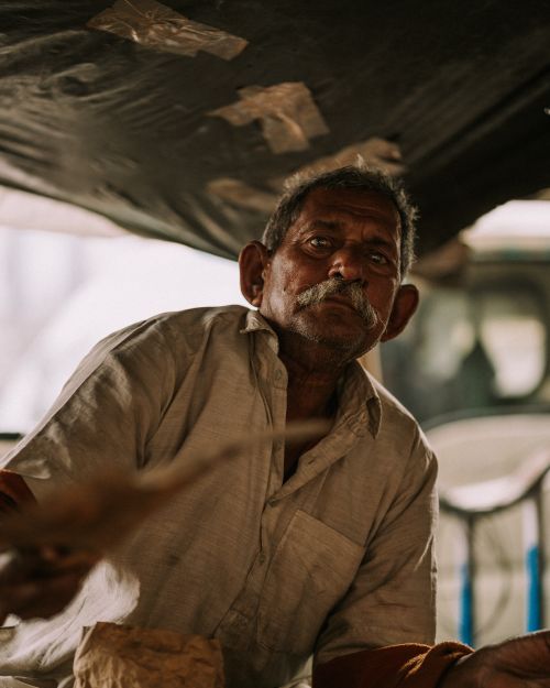 Free Elderly man with mustache poses under the shade, creating a dramatic portrait with natural lighting. Stock Photo