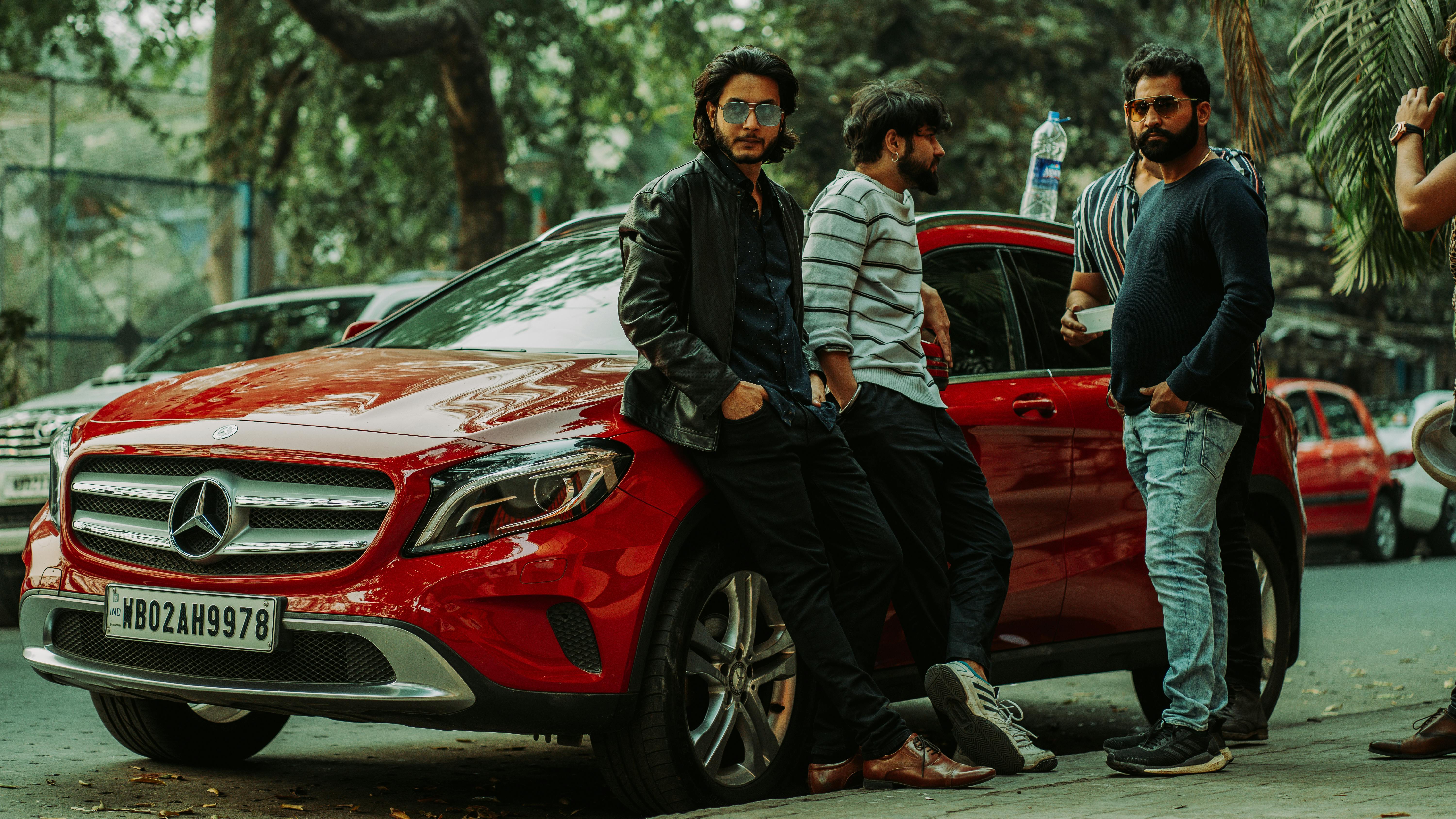 men standing beside a red car