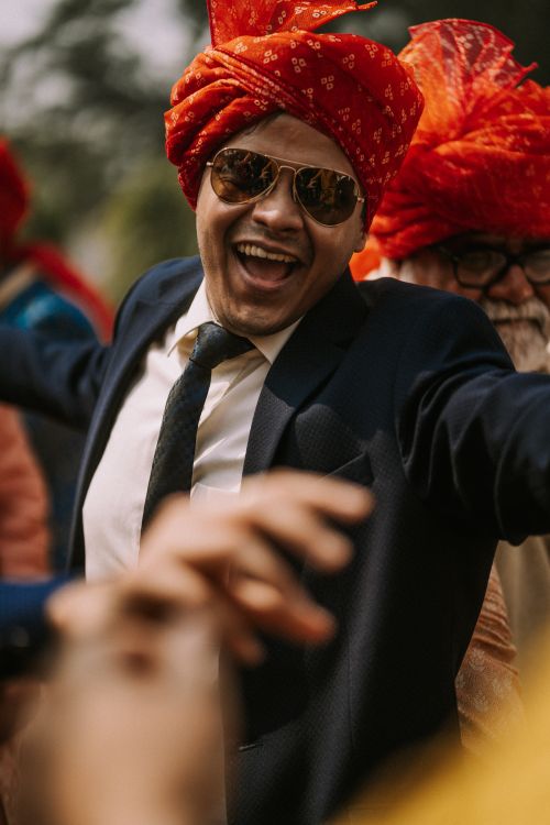 Free A man in a suit with a vibrant turban and sunglasses joyfully participates in an outdoor celebration. Stock Photo