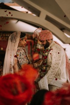 A vibrant Indian wedding scene featuring a couple in traditional attire, exchanging garlands.