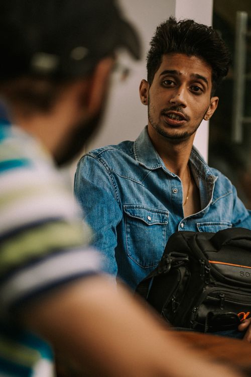 Free A young man in a denim shirt engaged in conversation holding a black bag indoors. Stock Photo