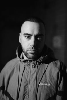 Striking black and white portrait of a man in a casual jacket, expressing intensity.