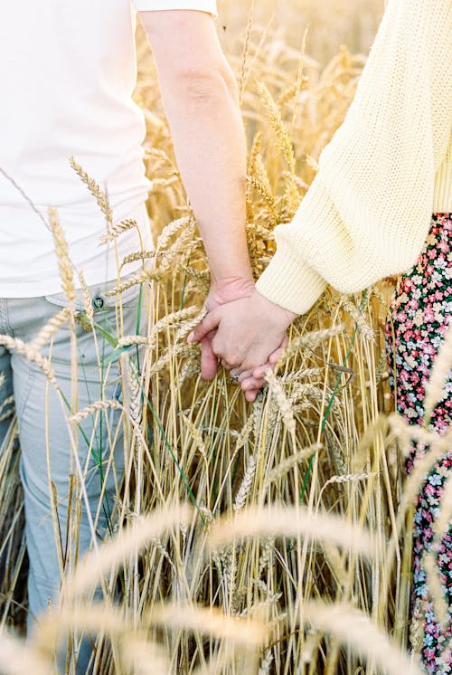 Close up of Couple Holding Hands on Field