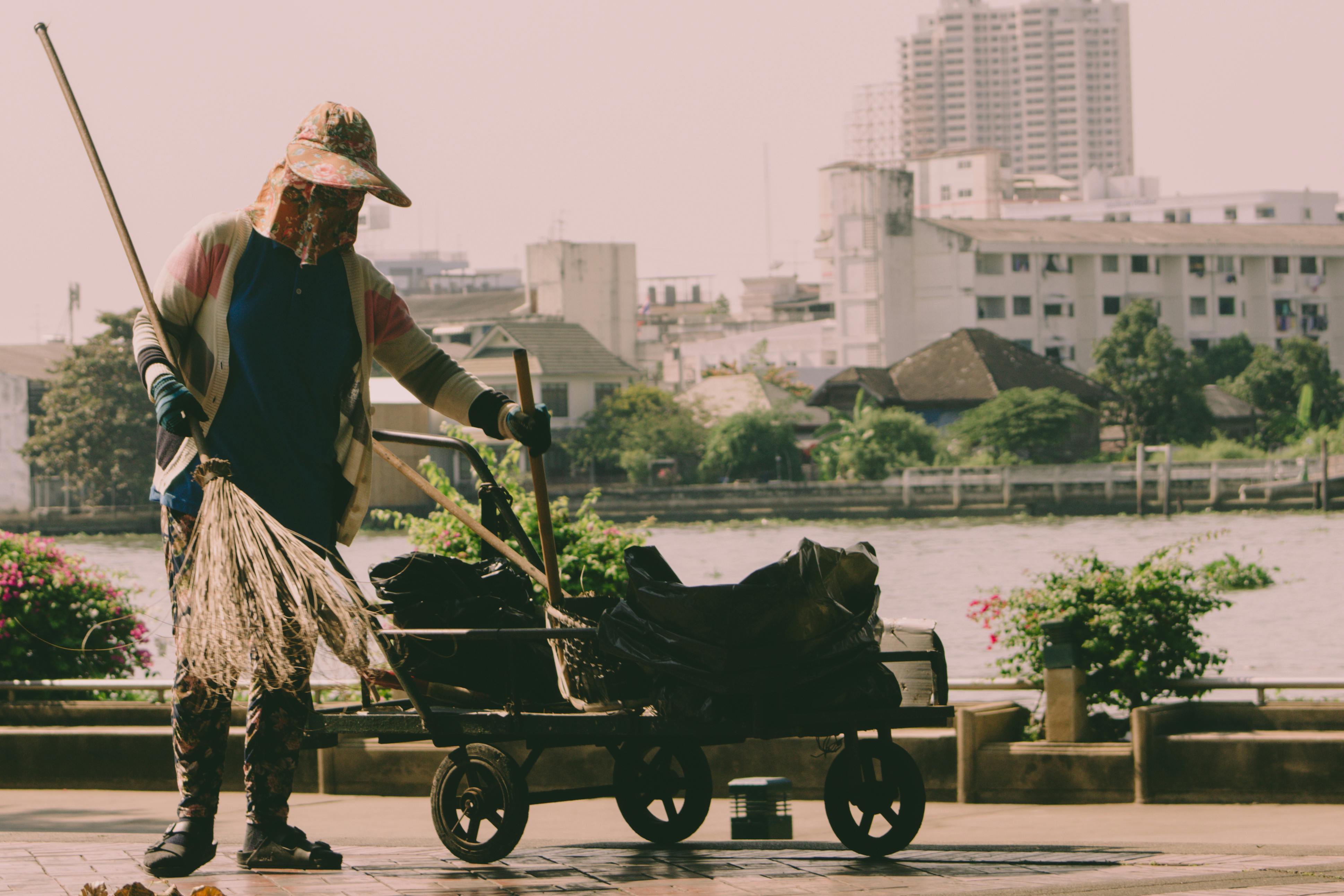 person holding broom and cart