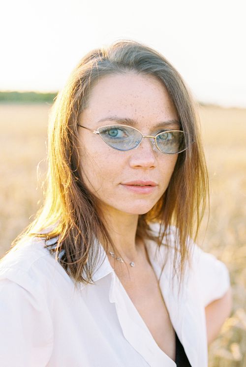 Free Portrait of a brunette woman wearing sunglasses in a sunlit field. Natural beauty and serenity. Stock Photo