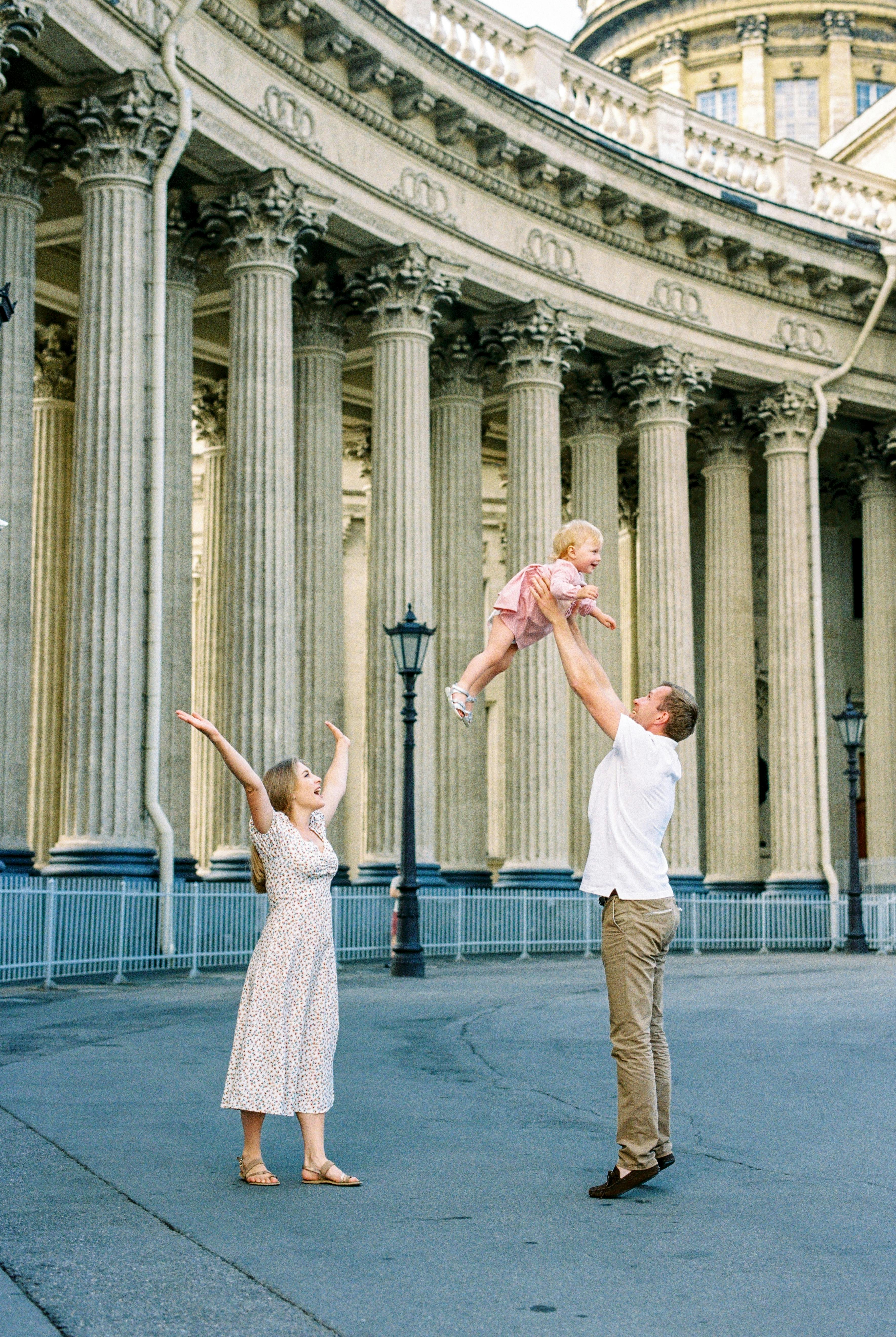 couple playing with their child in front of colonnade of kazan cathedral in saint petersburg russia