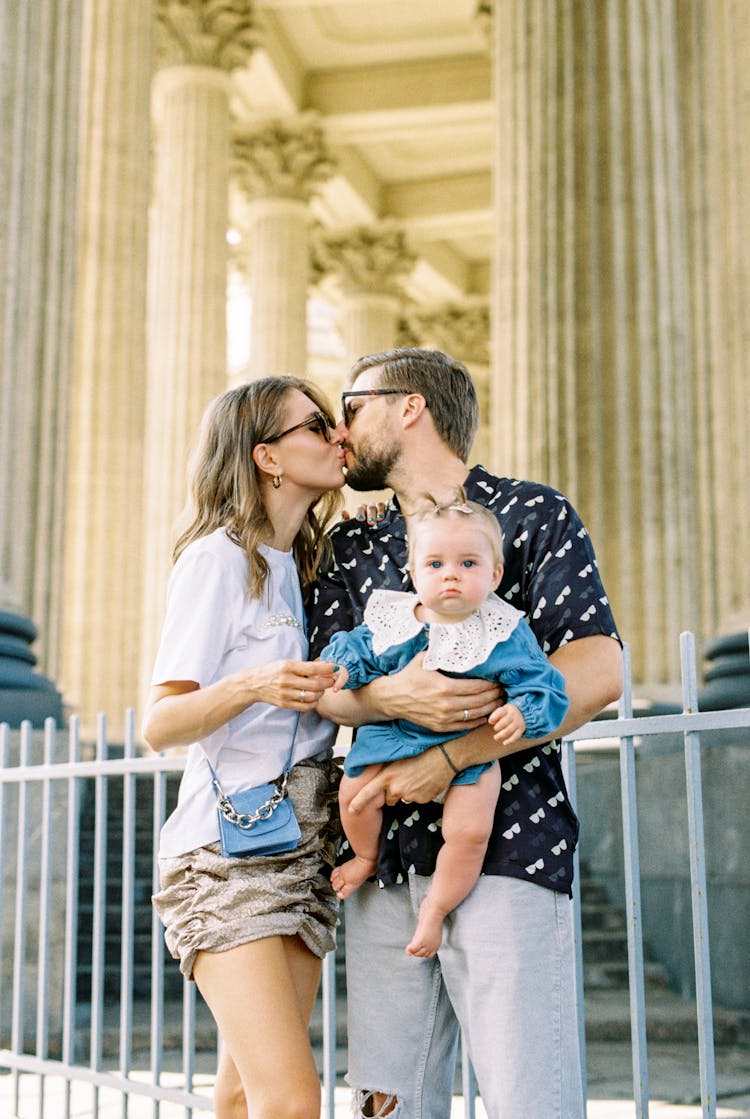 Man Carrying Baby Girl And Kissing Woman