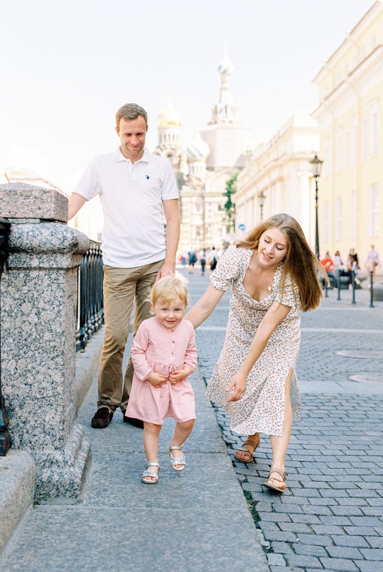 Parents Walking With Their Daughter