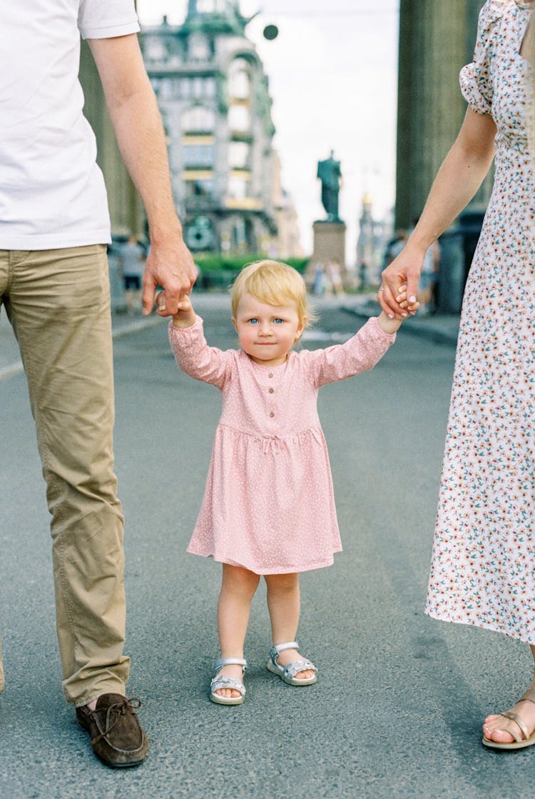 Cute Little Girl Standing Between Her Mom And Dad