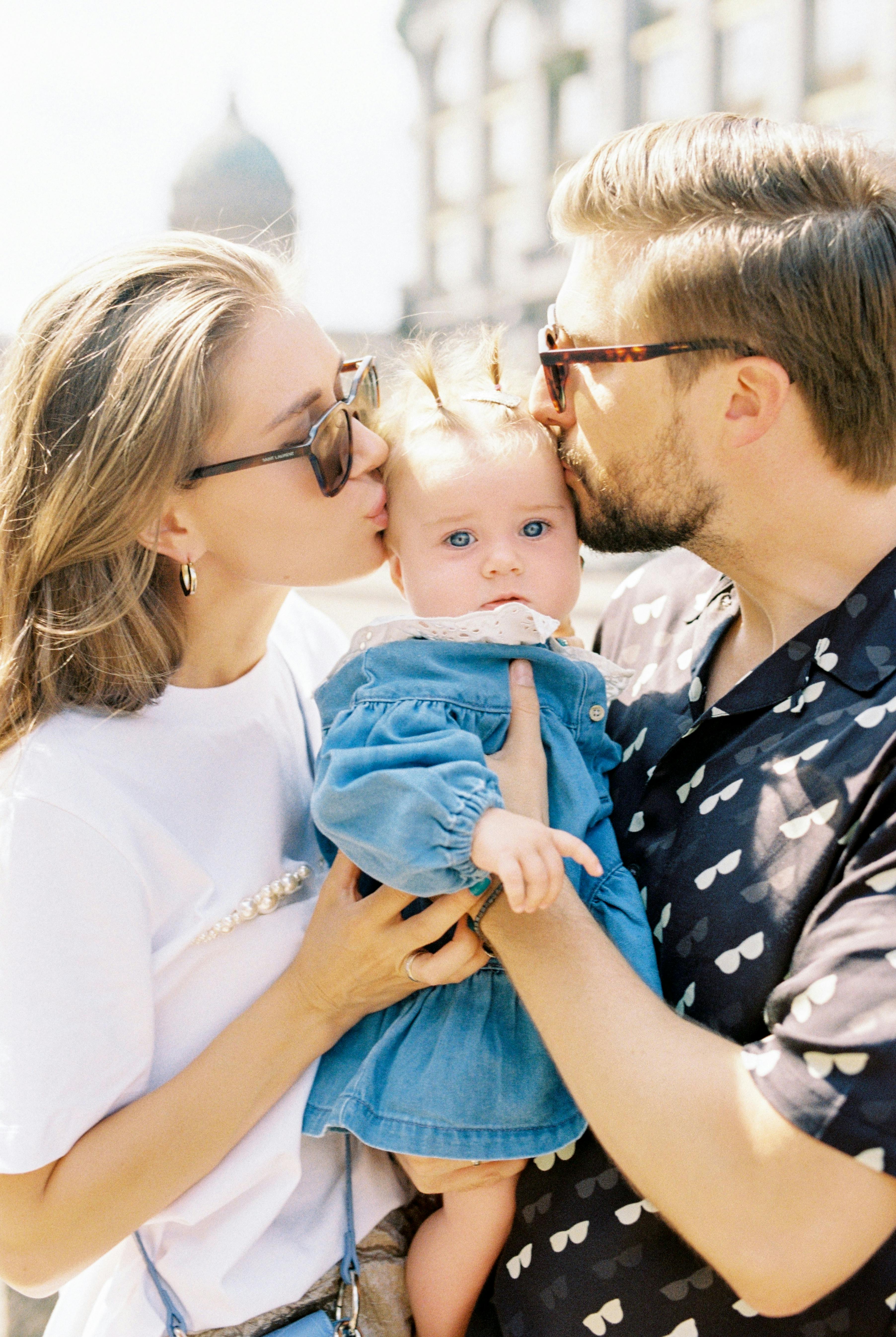 parents kissing their little cute girl