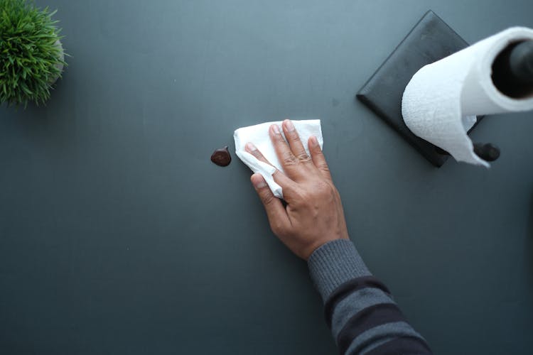 A Person Wiping A Table Using A Tissue Paper