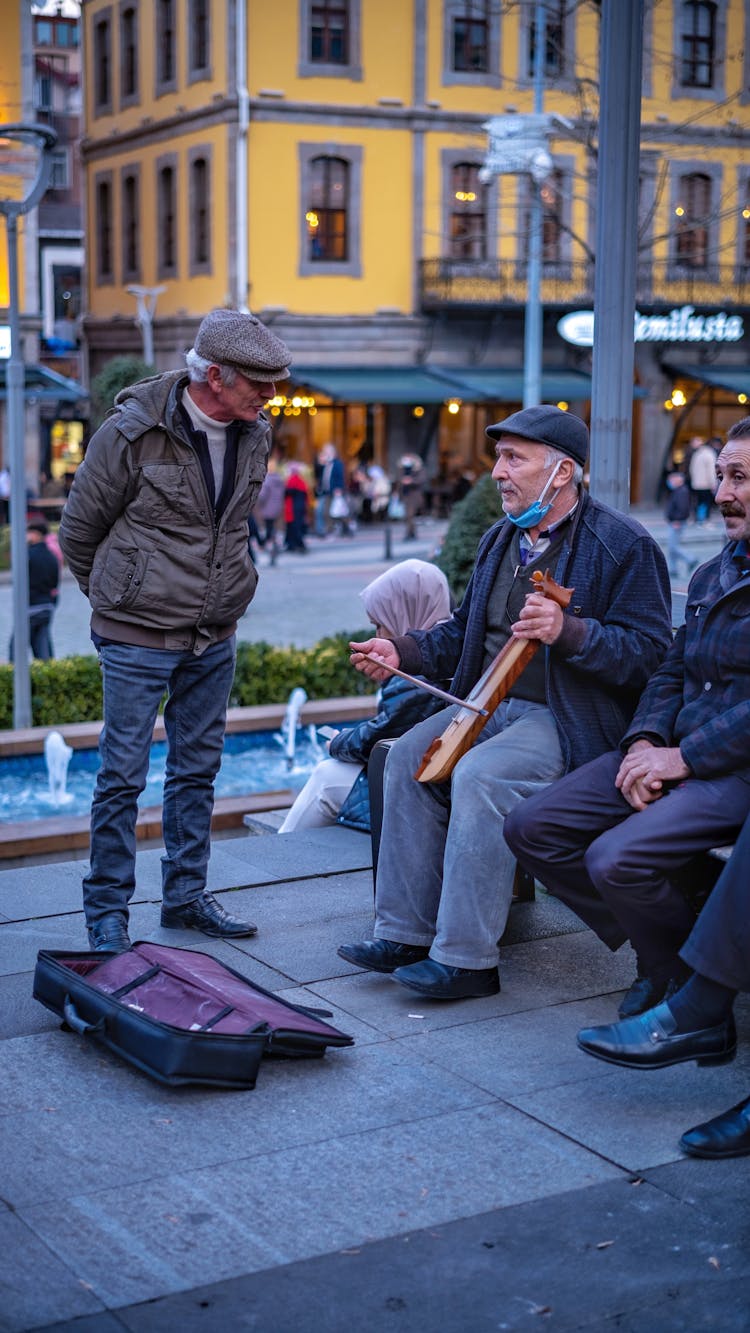 Men And Busker With Case On Pavement