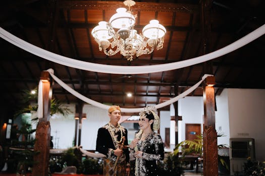 A couple in traditional Javanese attire during a wedding ceremony indoors, showcasing cultural heritage.