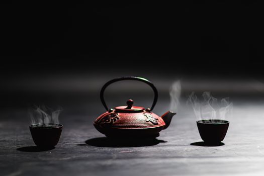 Minimalist image of a cast iron teapot and steaming cups, perfect for traditional tea culture themes.