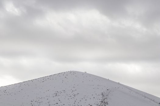 A peaceful snow-covered mountain peak with a cloudy sky, depicting winter serenity.