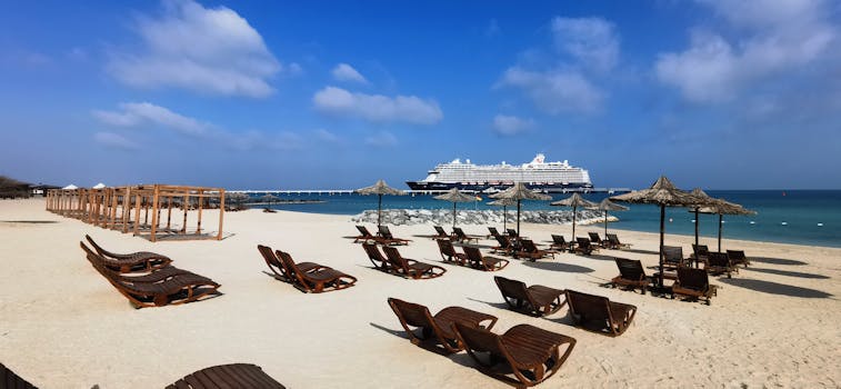 Relaxing beach scene with sun loungers and cruise ship on Sir Bani Yas, UAE. by Glenn Langhorst