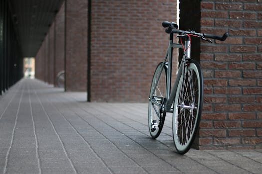 A modern bicycle leans against a brick wall in a quiet urban alleyway.
