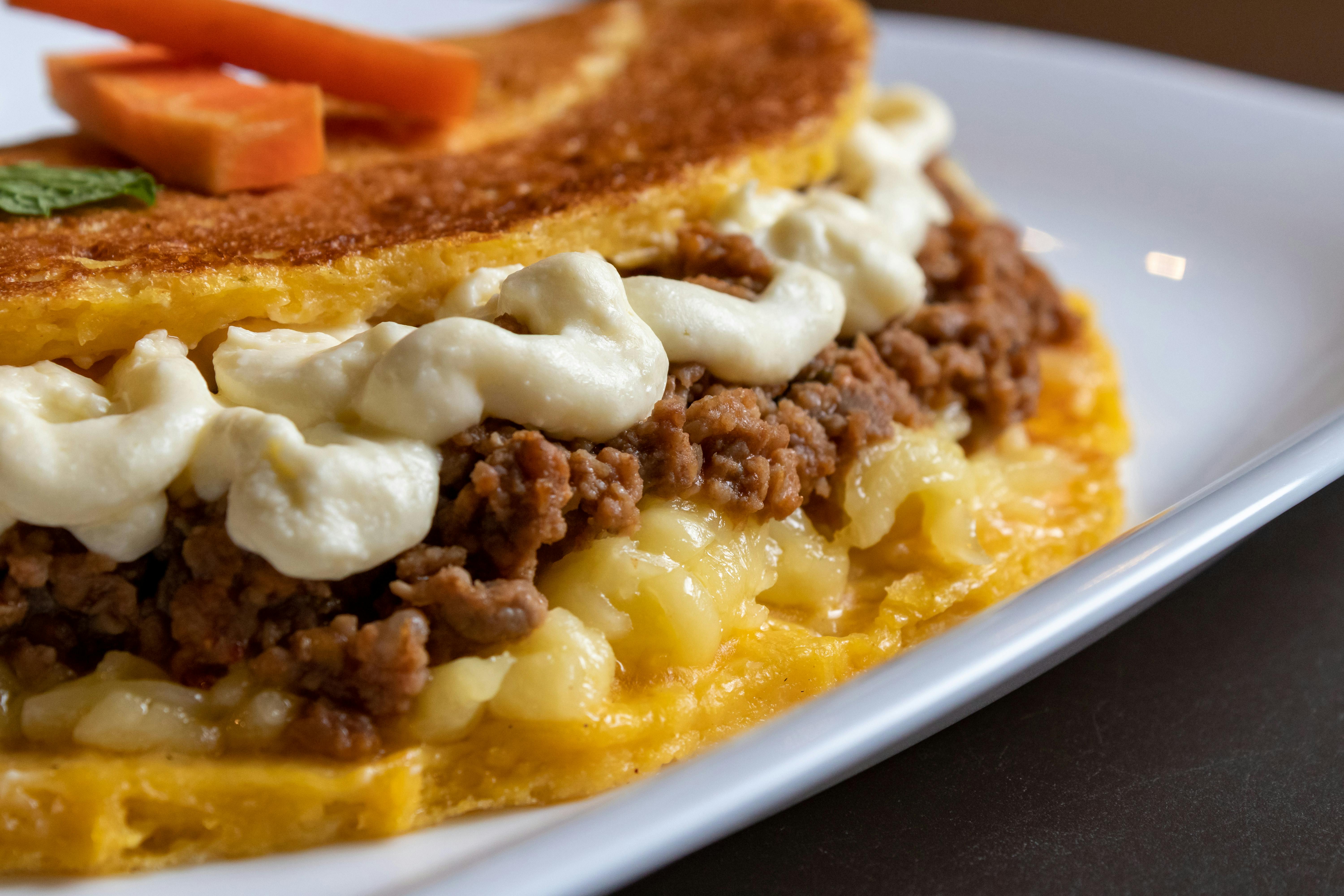 Mouth-watering close-up of a traditional Venezuelan cachapa with cheese and meat filling on a plate.