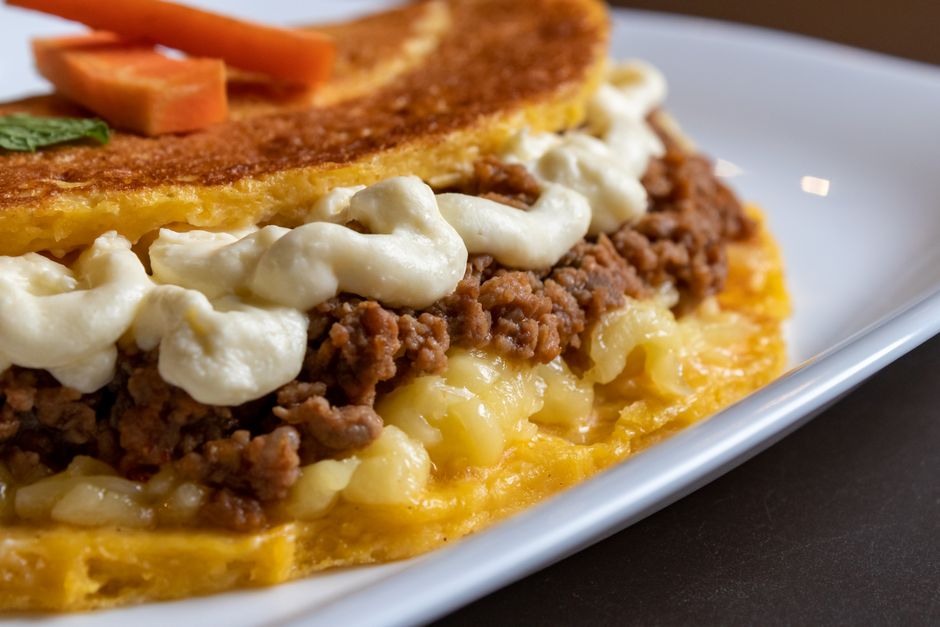 Thick round gorditas fried to a golden crust, one split open to show the steamy white interior stuffed with shredded beef, crumbled cheese, and lettuce