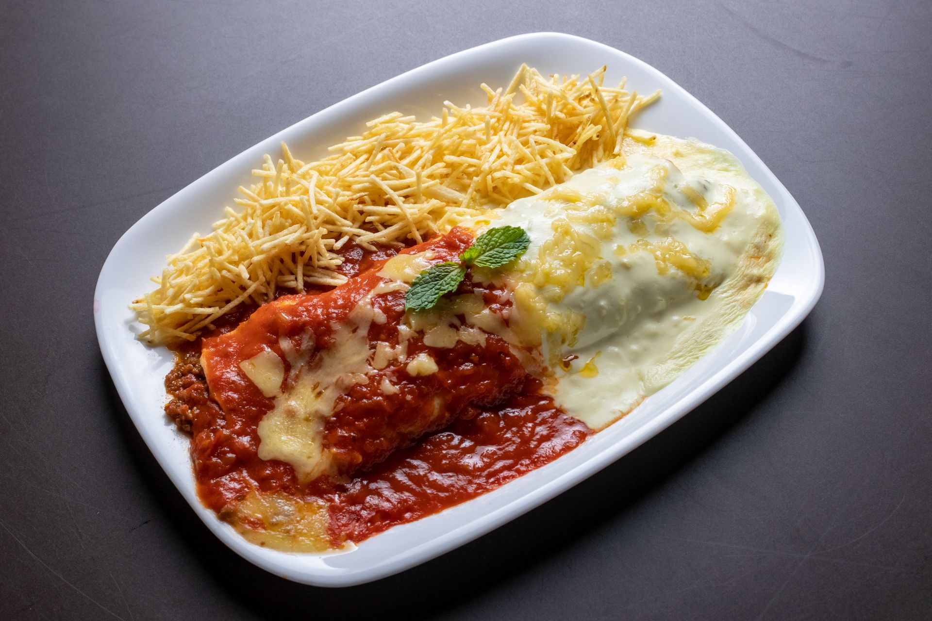 Appetizing pasta dish covered in rich tomato and cheese sauce served with crispy fries.